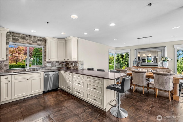 2336 Grand Ave, East Wenatchee, WA 98802 - kitchen featuring stainless steel dishwasher, a sink, a peninsula, dark countertops, and tasteful backsplash