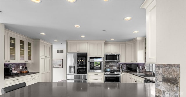 2336 Grand Ave, East Wenatchee, WA 98802 - kitchen with appliances with stainless steel finishes, dark countertops, recessed lighting, tasteful backsplash, and glass insert cabinets