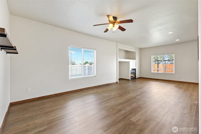 121 Scenic Dr NE, Moses Lake, WA 98837 - unfurnished living room featuring a ceiling fan, wood finished floors, a warm lit fireplace, recessed lighting, and baseboards