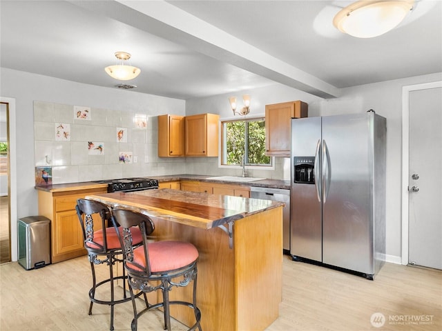 2101 Swanee Cir SE, Olympia, WA 98501 - kitchen with stainless steel appliances, light wood-style flooring, decorative backsplash, and a kitchen breakfast bar