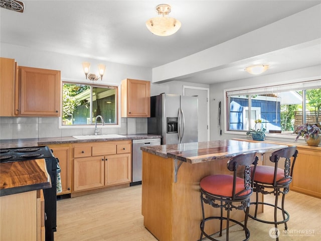 2101 Swanee Cir SE, Olympia, WA 98501 - kitchen with appliances with stainless steel finishes, light wood-style floors, a breakfast bar area, decorative backsplash, and a center island