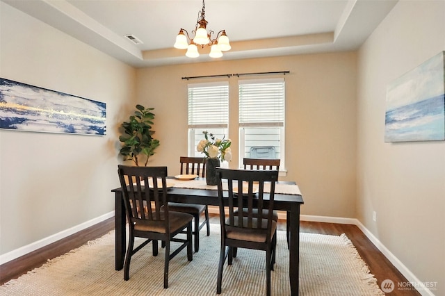2514 164th St E, Tacoma, WA 98445 - dining area featuring dark wood-style flooring, a chandelier, a tray ceiling, and baseboards