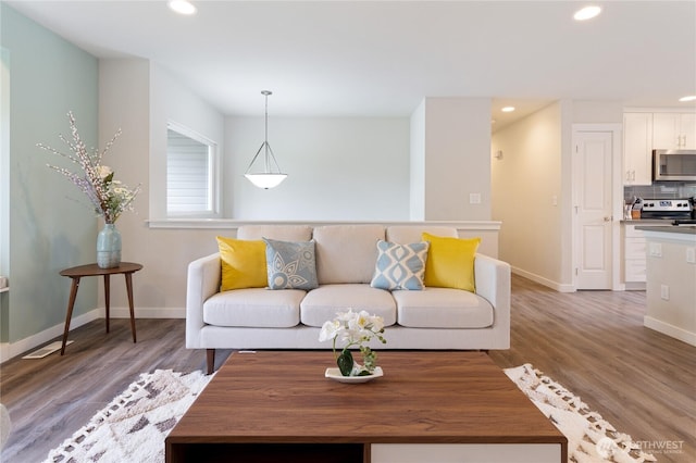 living area with recessed lighting, baseboards, and light wood-type flooring