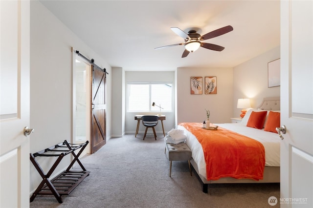 carpeted bedroom featuring a barn door, a ceiling fan, and baseboards