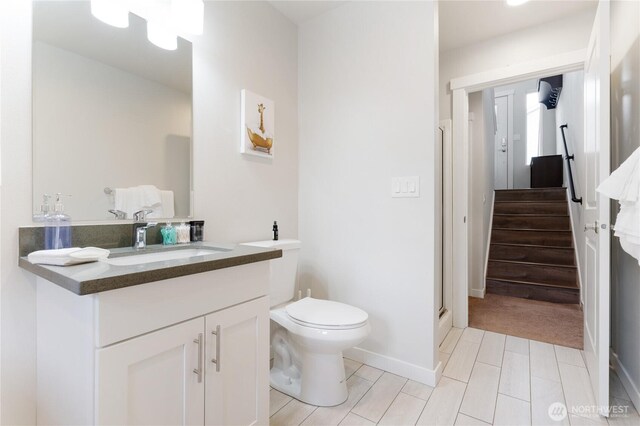 full bathroom featuring toilet, vanity, a shower, and baseboards