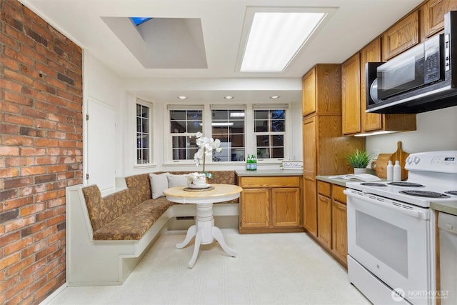 2607 NE 137th St, Seattle, WA 98125 - kitchen with white appliances, brick wall, brown cabinetry, and light flooring