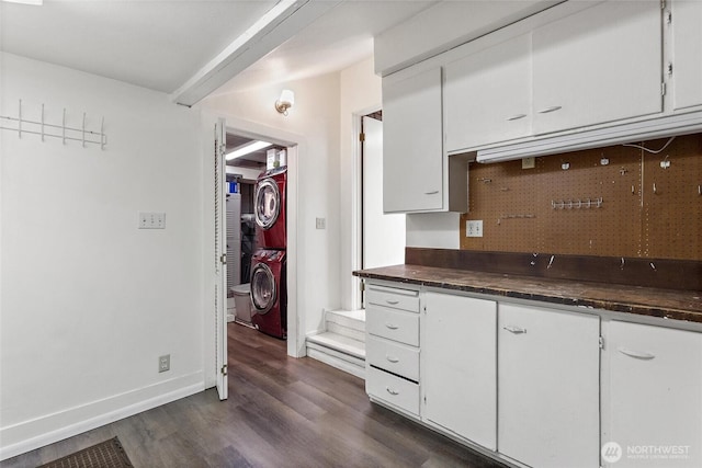 2607 NE 137th St, Seattle, WA 98125 - kitchen with estacked washer and dryer, dark countertops, white cabinetry, dark wood-type flooring, and baseboards