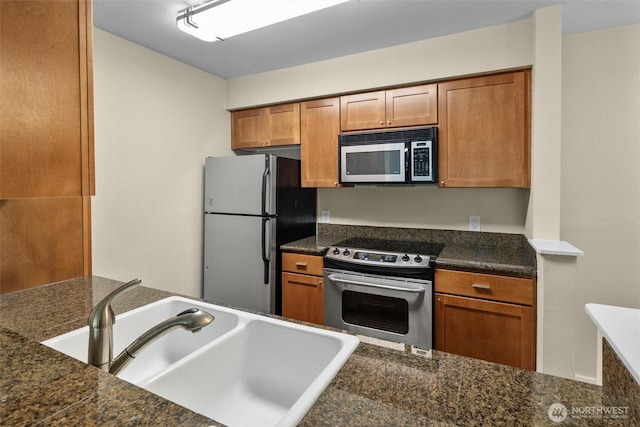 12303 Harbour Pointe Blvd Unit U109, Mukilteo, WA 98275 - kitchen featuring appliances with stainless steel finishes, a sink, brown cabinetry, and dark countertops