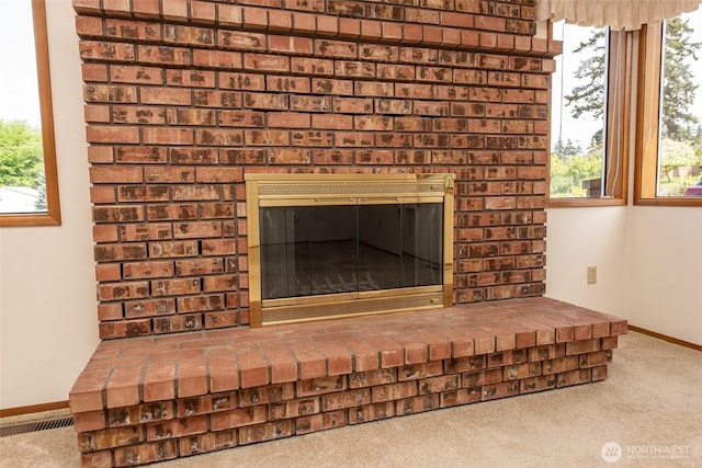 detailed view of carpet, baseboards, and a brick fireplace