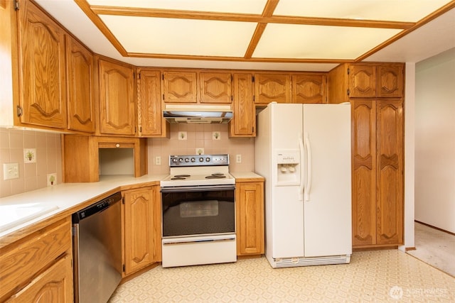 kitchen featuring white appliances, under cabinet range hood, light countertops, tasteful backsplash, and brown cabinets