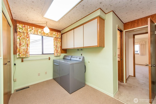 clothes washing area with cabinet space, independent washer and dryer, light colored carpet, and baseboards