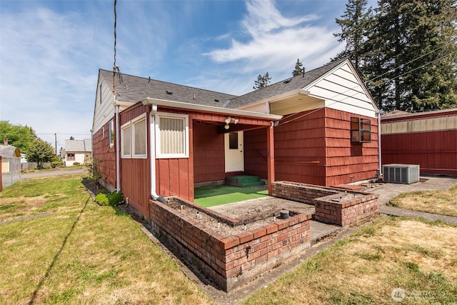 rear view of property featuring central AC and roof with shingles