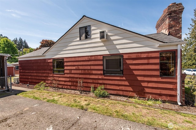 view of side of home with a chimney and a shingled roof