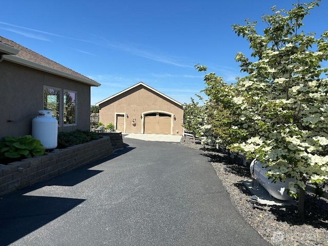 2702 N Levi St, Kennewick, WA 99338 - view of property exterior with asphalt driveway, stucco siding, roof with shingles, and an attached garage