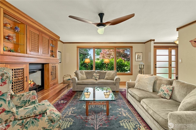 12211 SE 65th Pl, Bellevue, WA 98006 - living area featuring a lit fireplace, ornamental molding, wood finished floors, a ceiling fan, and baseboards