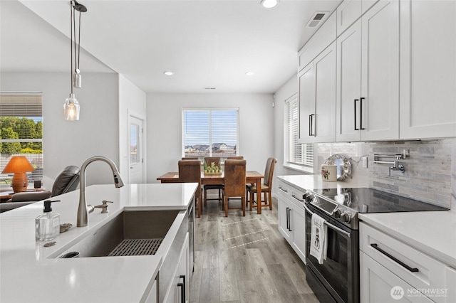 227 N Crestview Dr, Moses Lake, WA 98837 - kitchen featuring electric range oven, a sink, light wood-style floors, tasteful backsplash, and white cabinets