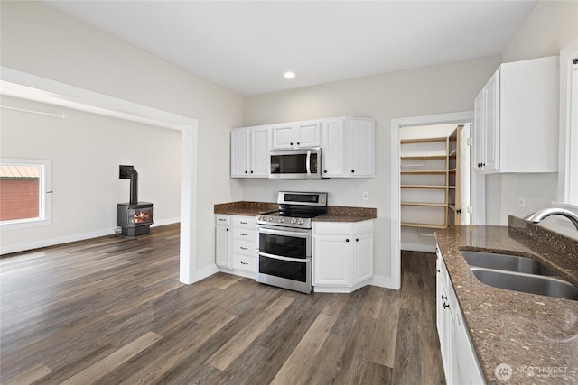 511 S 2nd St, Roslyn, WA 98941 - kitchen with stainless steel appliances, a sink, a wood stove, dark wood finished floors, and white cabinetry