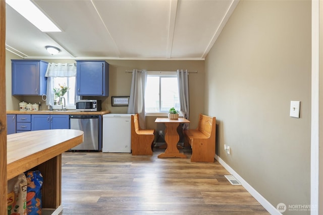 208 S Monroe St, Aberdeen, WA 98520 - kitchen with stainless steel appliances, blue cabinetry, lofted ceiling, butcher block countertops, and light wood-style floors