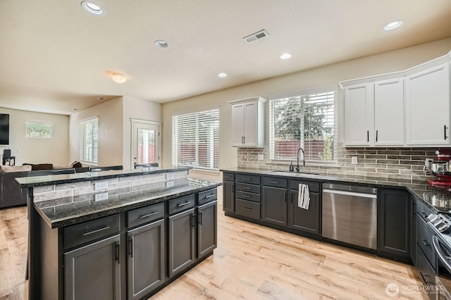 15281 Kayla St SE, Yelm, WA 98597 - kitchen with appliances with stainless steel finishes, a sink, white cabinets, a kitchen island, and tasteful backsplash