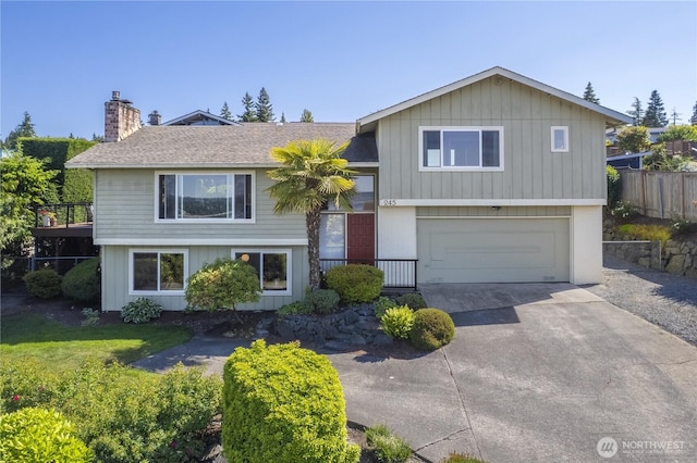 245 SW 298th Pl, Federal Way, WA 98023 - tri-level home with a garage, a chimney, driveway, a shingled roof, and board and batten siding