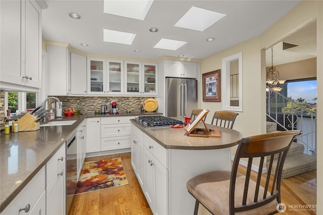 245 SW 298th Pl, Federal Way, WA 98023 - kitchen with stainless steel appliances, a sink, a breakfast bar area, light wood-style flooring, and tasteful backsplash