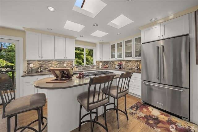245 SW 298th Pl, Federal Way, WA 98023 - kitchen featuring appliances with stainless steel finishes, a skylight, a kitchen breakfast bar, white cabinetry, and glass insert cabinets