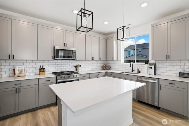12605 179th St E, Puyallup, WA 98374 - kitchen featuring appliances with stainless steel finishes, gray cabinets, a sink, a center island, and light wood-style flooring