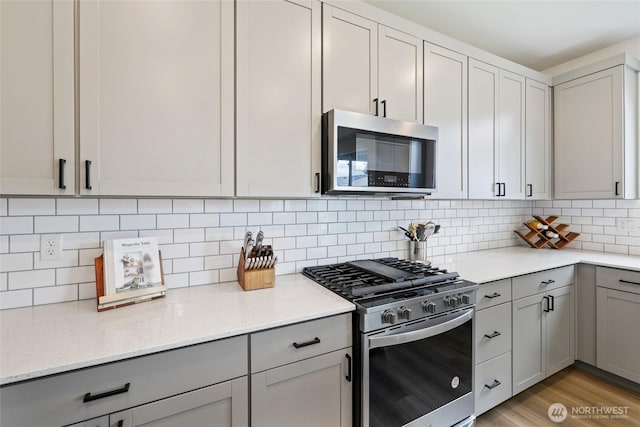 12605 179th St E, Puyallup, WA 98374 - kitchen with stainless steel appliances, gray cabinets, light stone countertops, and decorative backsplash