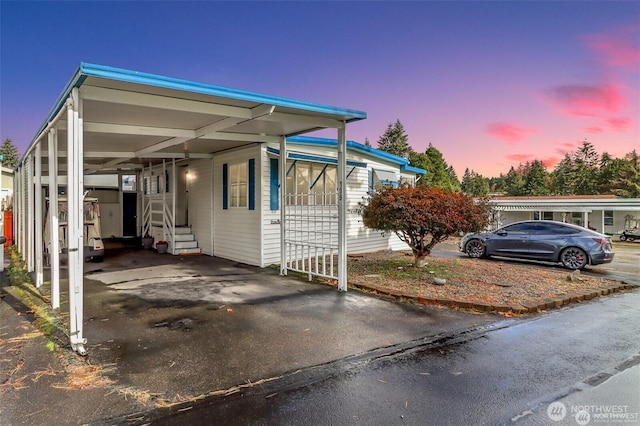 view of front of property featuring an attached carport, entry steps, and asphalt driveway