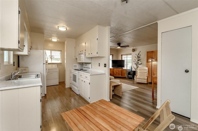 kitchen with white appliances, washer / dryer, a sink, light countertops, and white cabinetry