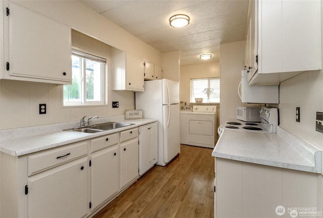 kitchen with a sink, washer and dryer, white appliances, and plenty of natural light