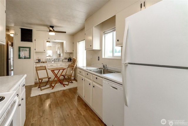 kitchen with white appliances, a sink, light countertops, and light wood-style flooring
