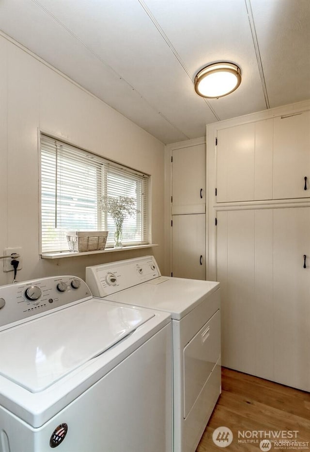 clothes washing area with separate washer and dryer, light wood-style floors, and cabinet space