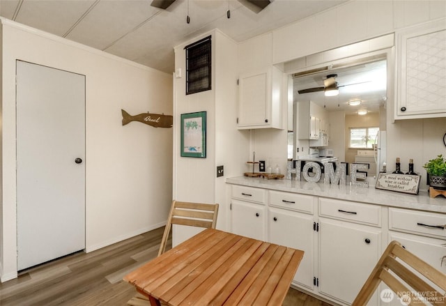 kitchen featuring a ceiling fan, white cabinetry, wood finished floors, and crown molding