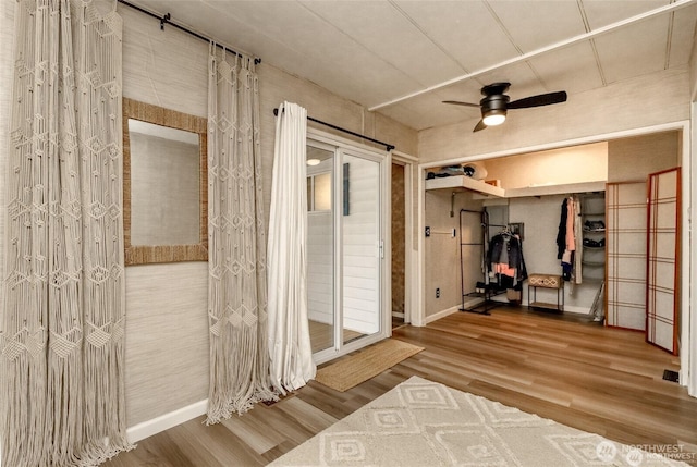 unfurnished bedroom with wood finished floors, baseboards, access to outside, and a ceiling fan
