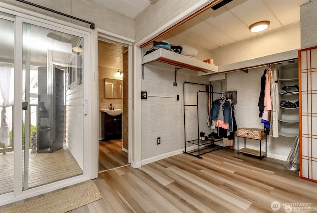 unfurnished bedroom featuring light wood-style flooring, a sink, baseboards, and ensuite bath