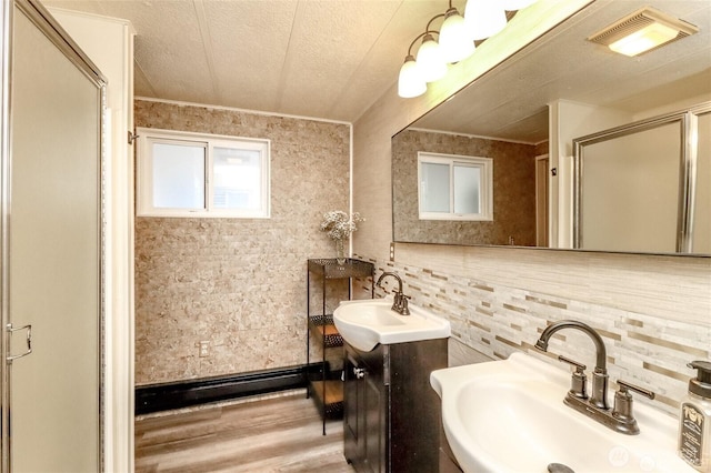 bathroom featuring a sink, backsplash, a stall shower, ornamental molding, and a textured ceiling