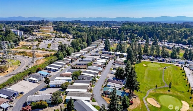aerial view of residential area with a mountain backdrop, a heavily wooded area, and a local golf course