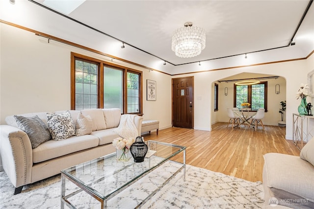 6026 35th Ave NE, Seattle, WA 98115 - living room featuring arched walkways, rail lighting, a chandelier, light wood-type flooring, and baseboards