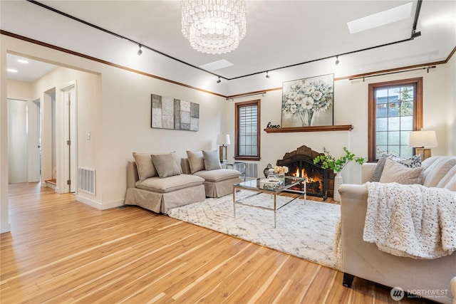 6026 35th Ave NE, Seattle, WA 98115 - living room with rail lighting, a skylight, wood finished floors, a brick fireplace, and a chandelier