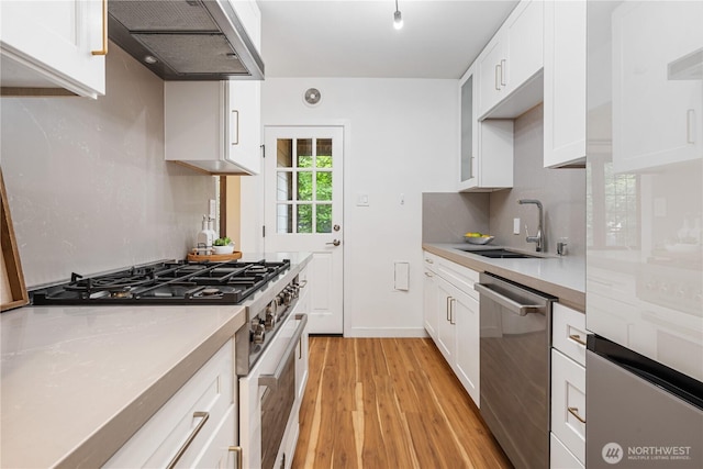 6026 35th Ave NE, Seattle, WA 98115 - kitchen with gas range oven, dishwasher, range hood, a sink, and light wood-type flooring