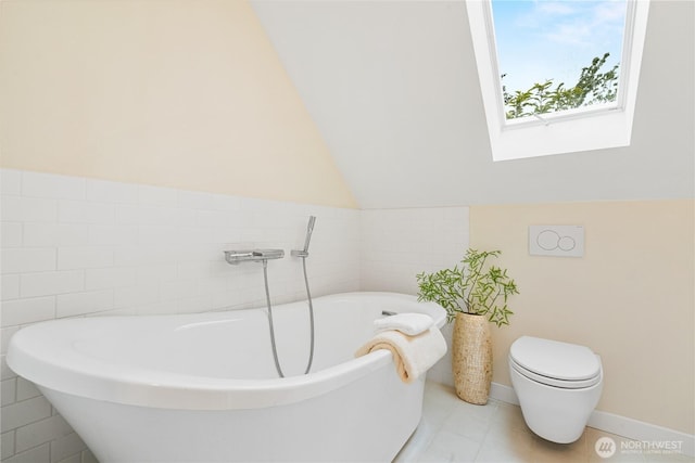 6026 35th Ave NE, Seattle, WA 98115 - bathroom with a freestanding tub, a skylight, vaulted ceiling, tile patterned flooring, and toilet