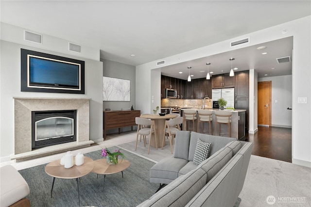 living room featuring a premium fireplace, baseboards, recessed lighting, and light wood finished floors
