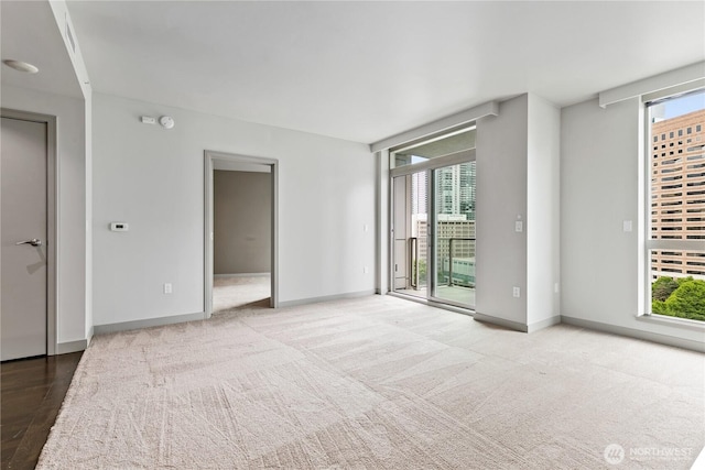 empty room featuring healthy amount of natural light, baseboards, and carpet