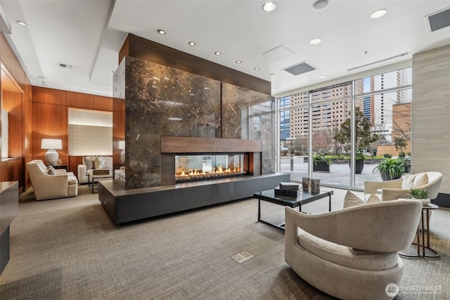 building lobby featuring floor to ceiling windows, wood walls, a view of city, and recessed lighting