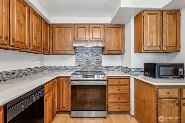 132 N 132nd Unit 202, Seattle, WA 98133 - kitchen featuring black appliances, under cabinet range hood, brown cabinets, light countertops, and light wood-type flooring