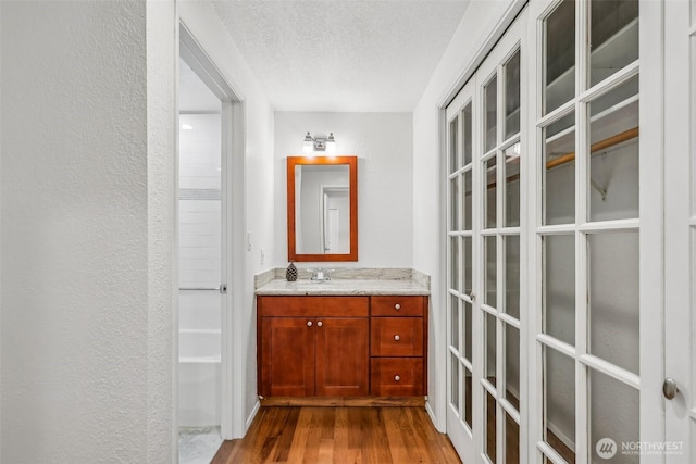 132 N 132nd Unit 202, Seattle, WA 98133 - bathroom with a textured ceiling, wood finished floors, vanity, and a textured wall
