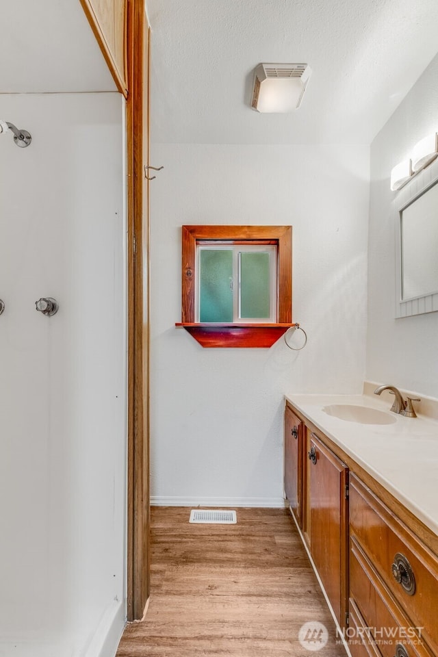 7311 Chambers Creek Rd W Unit 37, University Place, WA 98467 - bathroom with vanity, wood finished floors, a textured ceiling, baseboards, and a shower