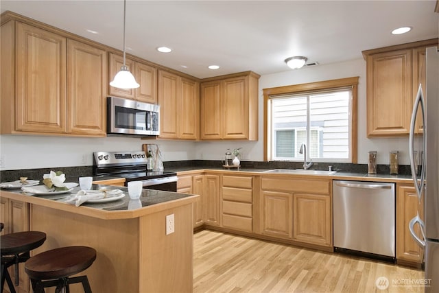 8515 Stone Ave N Unit A & B, Seattle, WA 98103 - kitchen featuring stainless steel appliances, a peninsula, a sink, a breakfast bar, and light wood finished floors
