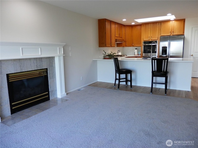 7819 Amethyst Loop NW, Silverdale, WA 98383 - kitchen with stainless steel appliances, tasteful backsplash, under cabinet range hood, a breakfast bar, and light carpet